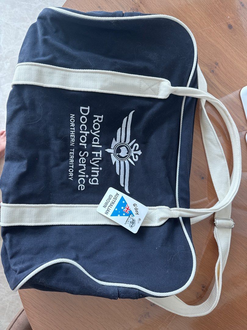 Royal Flying Doctor Service Canvas Bag (Category: Tote Bags) located in Singapore. Submitted by sgboater (Listing ID 1377577019, Image 1). Description: Check out this brand new canvas bag from the Royal Flying Doctor Service! It's made in Australia and features the organization's logo. The bag is navy blue with cream-colored straps and trim. It's perfect for carrying your essentials. The bag is new with tags attached. It's a great find for anyone