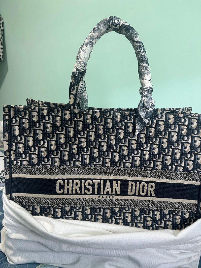 Christian Dior Book Tote Bag (Category: Bags & Wallets) located in Singapore. Submitted by miumeow7 (Listing ID 1377911789, Image 3). Description: Authentic Christian Dior Book Tote Bag. Features the iconic Dior Oblique pattern. Includes a scarf wrapped around the handles. In excellent condition, perfect for everyday use or special occasions. Condition 10/10 Comes with original receipt Brand new, unused and just stored in cupboard .