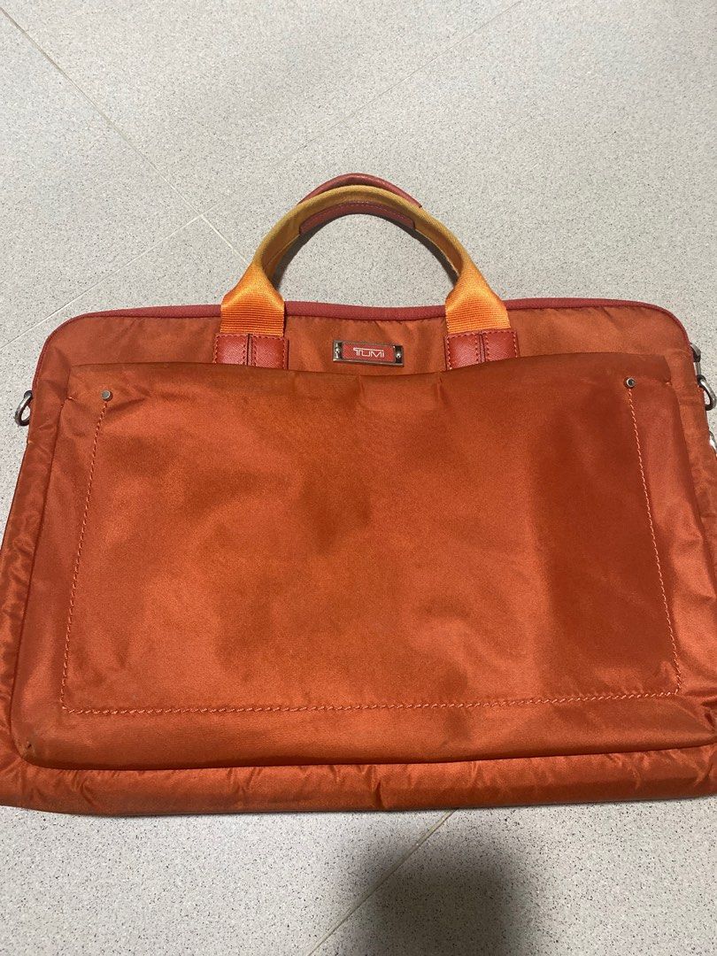 Tumi Orange Laptop Bag (Category: Laptop Bags & Sleeves) located in Singapore. Submitted by cuuawwihmi (Listing ID 1377892297, Image 3). Description: This is a pre-owned Tumi laptop bag in orange. It has a top handle and a shoulder strap. The bag shows signs of wear, including some marks on the exterior. The interior appears to be in good condition. Perfect for carrying your laptop and other essentials..