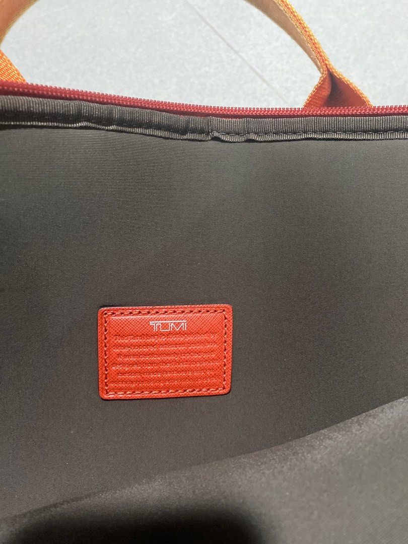 Tumi Orange Laptop Bag (Category: Laptop Bags & Sleeves) located in Singapore. Submitted by cuuawwihmi (Listing ID 1377892297, Image 1). Description: This is a pre-owned Tumi laptop bag in orange. It has a top handle and a shoulder strap. The bag shows signs of wear, including some marks on the exterior. The interior appears to be in good condition. Perfect for carrying your laptop and other essentials..
