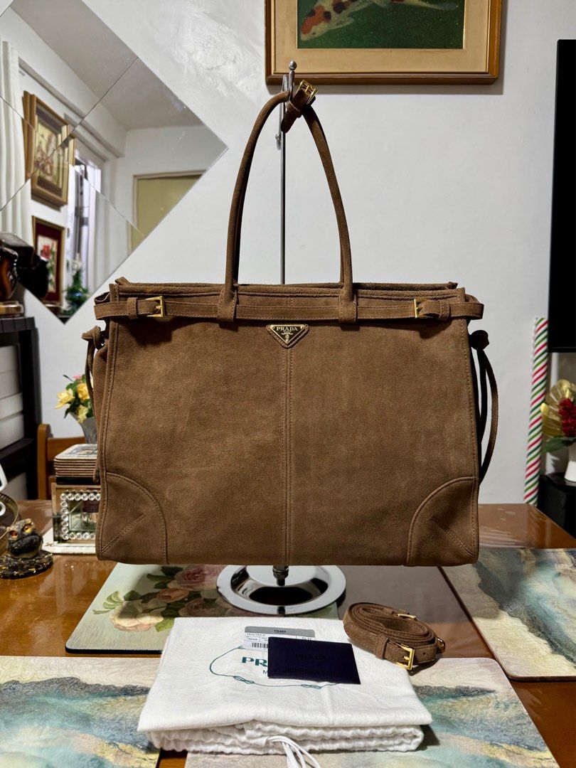PRADA SUEDE TOTE BAG (Category: Luxury Bags & Wallets) located in Cavite. Submitted by carrycouturebymsu (Listing ID 1379907398, Image 1). Description: • Calf suede outer 100% • Choco brown color • With top zip-fastening, buckle-strap fastening, internal zip-fastening pocket and circular top handles • 🇯🇵 Self Authentication is advised • Coded. Made in Italy • Actual pic posted • What you see is what you get Measurement : 17 x 36 x 50 cm Inclusi