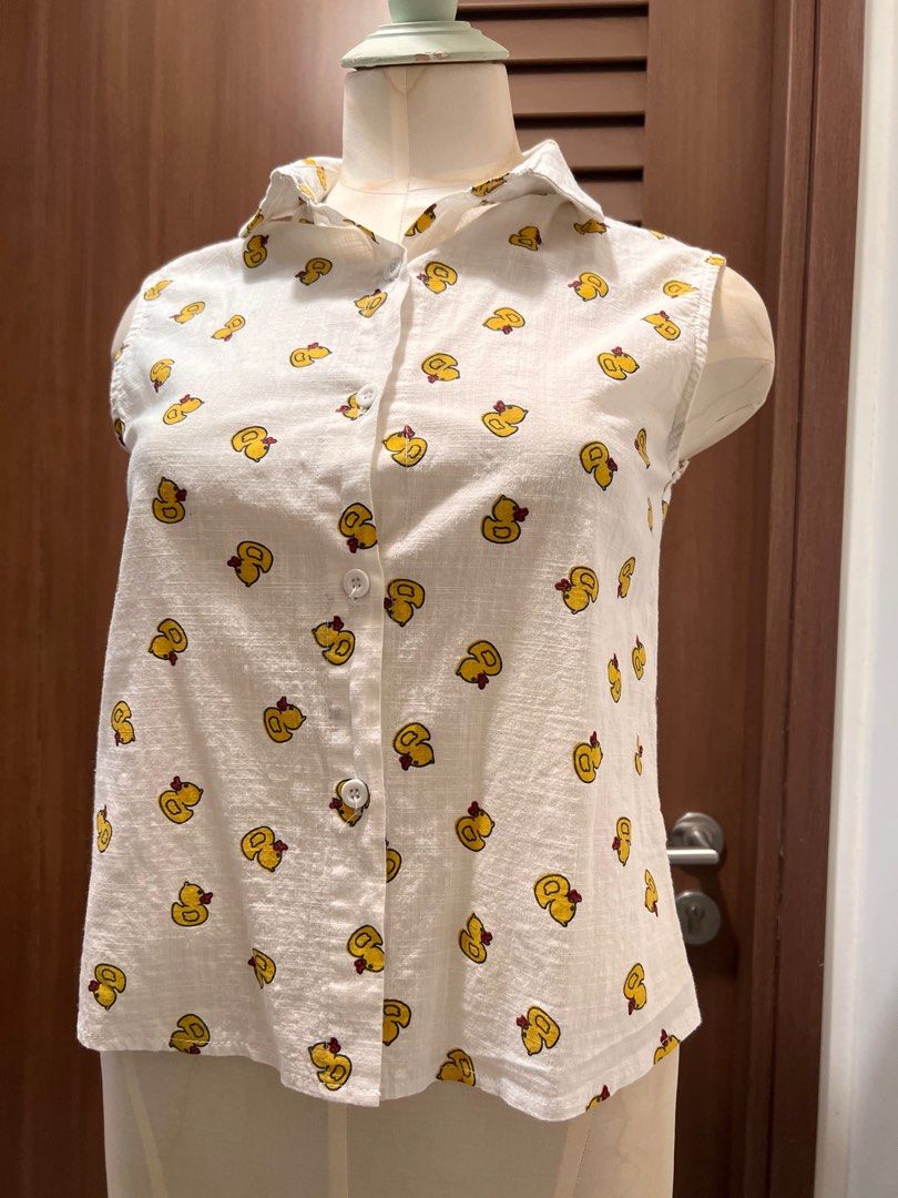Playful Duck Print Sleeveless Shirt (Category: Shirts) located in Singapore. Submitted by minni3scloset (Listing ID 1380263997, Image 2). Description: Cheerful and lightweight, this sleeveless shirt is adorned with a fun all-over yellow duck print, perfect for casual sunny days. The button-down front and pointed collar add a touch of structure to the relaxed silhouette. Made from breathable fabric with a soft texture, it’s both cute and comfortab