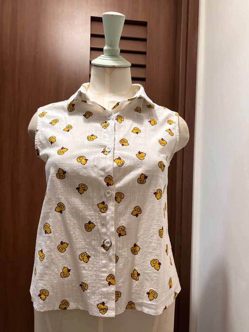 Playful Duck Print Sleeveless Shirt (Category: Shirts) located in Singapore. Submitted by minni3scloset (Listing ID 1380263997, Image 1). Description: Cheerful and lightweight, this sleeveless shirt is adorned with a fun all-over yellow duck print, perfect for casual sunny days. The button-down front and pointed collar add a touch of structure to the relaxed silhouette. Made from breathable fabric with a soft texture, it’s both cute and comfortab