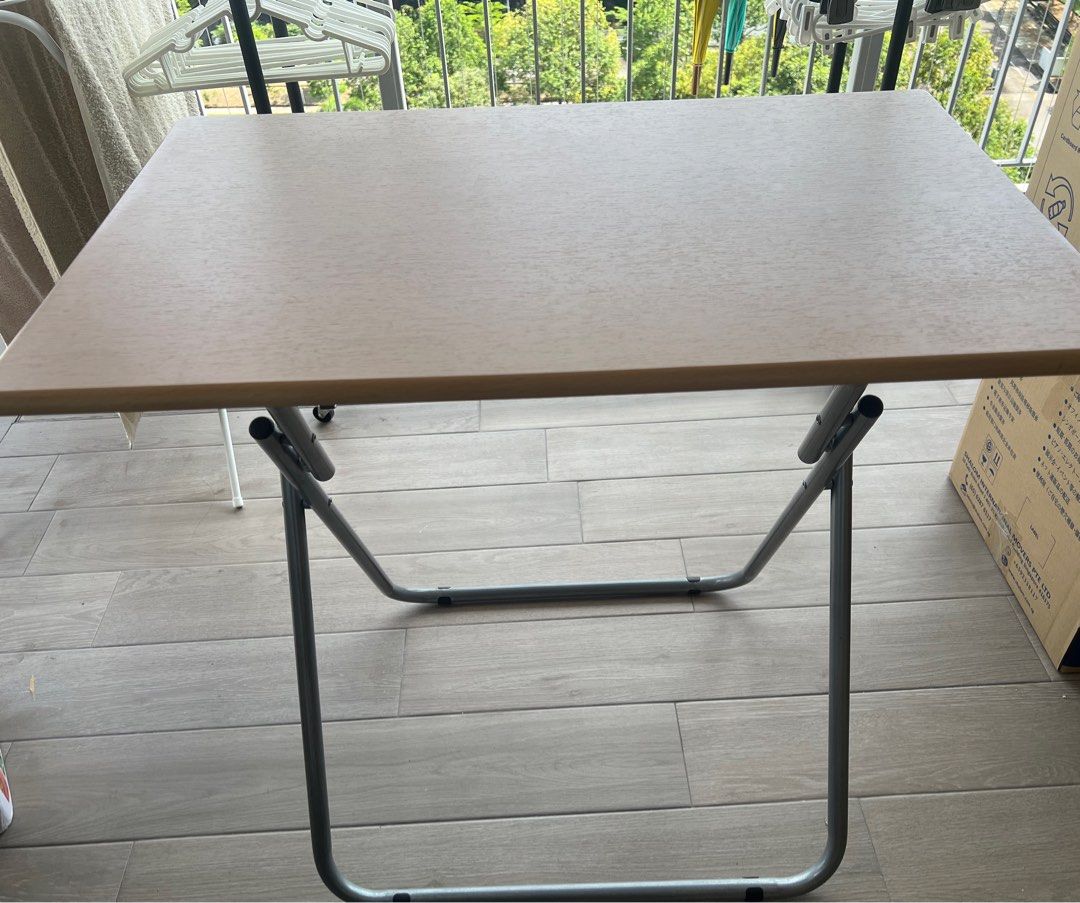 Foldable Square Table (Category: Tables & Sets) located in Singapore. Submitted by babymama_kloset (Listing ID 1380301563, Image 2). Description: Foldable square table. Perfect for small spaces or temporary use. The table is in good condition and folds up easily for storage. It has a brown tabletop and a metal frame. .