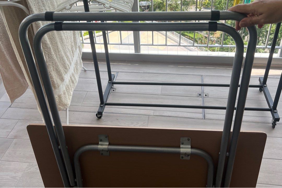 Foldable Square Table (Category: Tables & Sets) located in Singapore. Submitted by babymama_kloset (Listing ID 1380301563, Image 1). Description: Foldable square table. Perfect for small spaces or temporary use. The table is in good condition and folds up easily for storage. It has a brown tabletop and a metal frame. .