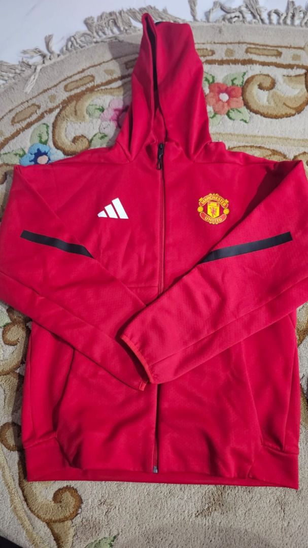 Adidas Manchester United Hoodie - Red - Size L (Category: Coats, Jackets and Outerwear) located in Singapore. Submitted by kyzre96 (Listing ID 1380506497, Image 1). Description: Official Adidas Manchester United hoodie in red. Features the team crest and Adidas logo. Has a full zip and a hood. Size L. Made in Cambodia. Great for any Man U fan! Got it as a gift last month. Wrong size. Oversize for me. Never use and never wash. Follow the Asian Siz