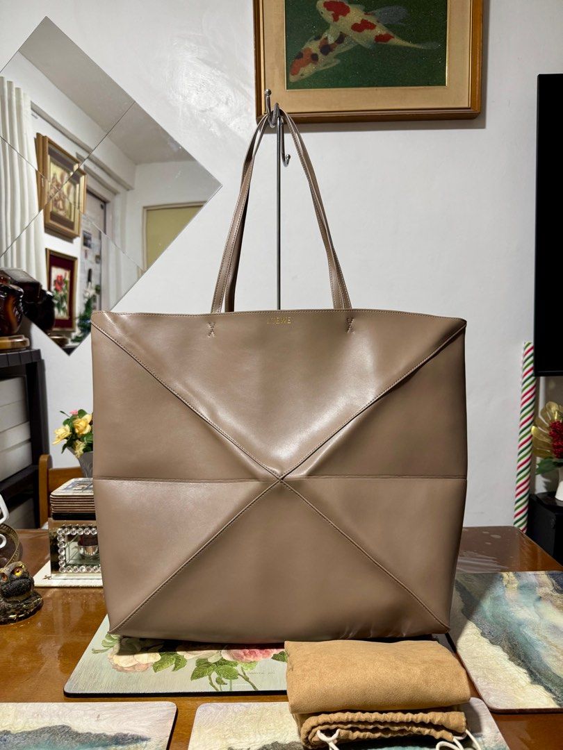 LOEWE XL Puzzle Fold Tote Bag (Category: Luxury Bags & Wallets) located in Cavite. Submitted by carrycouturebymsu (Listing ID 1380690637, Image 1). Description: • Calf leather 100% • Folded design in tan/taupe with two flat shoulder straps, logo stamp to the front, smooth grain, no fastening, suede lining and main compartment. • No additional photos • 🇯🇵 Self Authentication is advised • Coded/ Made in Spain • Actual pic posted • What you see is