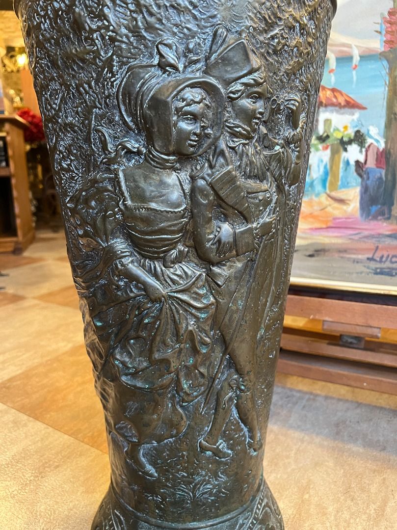 由 19th.antique (刊登 ID 1380777580，圖片 2) 提交，位於 台北市 (Taipei) 的 【🇫🇷 法國・手工銅浮雕傘桶・新藝術風格】 #624037 (類別：居家改善及收納用品)，說明：【🇫🇷 法國・手工銅浮雕傘桶・新藝術風格】 這件來自法國的百年古董傘桶／手杖桶，是19世紀末至20世紀初「Art Nouveau 新藝術風格」的絕佳代表作之一。整體以厚實銅材手工鍛鑄而成，表面浮雕細緻生動，承襲了新藝術時期對自然形態與曲線的極致追求。 正面主體浮雕描繪一對著傳統服飾的貴族男女，男子手持單筒望遠鏡，女子裙襬飛揚，兩人神情悠然愉悅，體現了19世紀末歐洲上層社會的浪漫生活氛圍。 上方板則飾以繩結花籃與藤蔓果實的浮雕圖樣，藤蔓纏繞交織、果實飽滿，配上自然彎曲的枝條與飄帶，正是新藝術風強調的自然元素與裝飾性設計的融合。 底部則以海螺與植物葉飾為基底，整體輪廓流暢高雅，展現藝術性與實用性兼具的設計精神。 🔸 製作工藝：手工銅雕 🔸 藝術風格：Art Nouve