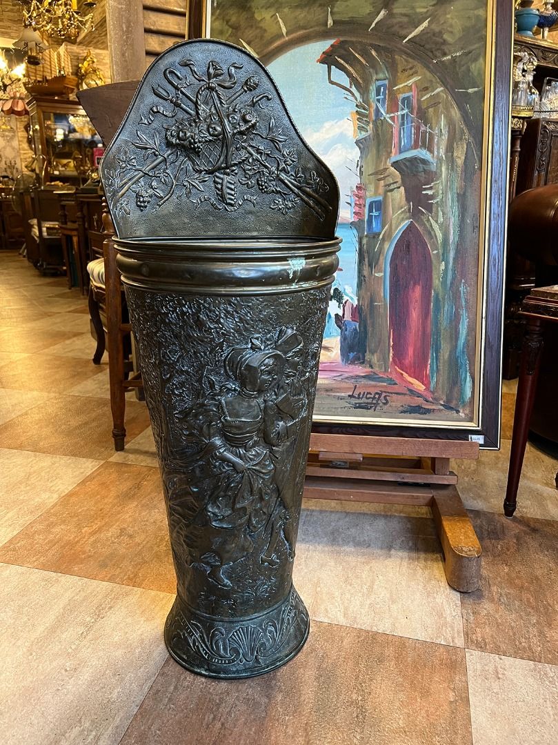 由 19th.antique (刊登 ID 1380777580，圖片 1) 提交，位於 台北市 (Taipei) 的 【🇫🇷 法國・手工銅浮雕傘桶・新藝術風格】 #624037 (類別：居家改善及收納用品)，說明：【🇫🇷 法國・手工銅浮雕傘桶・新藝術風格】 這件來自法國的百年古董傘桶／手杖桶，是19世紀末至20世紀初「Art Nouveau 新藝術風格」的絕佳代表作之一。整體以厚實銅材手工鍛鑄而成，表面浮雕細緻生動，承襲了新藝術時期對自然形態與曲線的極致追求。 正面主體浮雕描繪一對著傳統服飾的貴族男女，男子手持單筒望遠鏡，女子裙襬飛揚，兩人神情悠然愉悅，體現了19世紀末歐洲上層社會的浪漫生活氛圍。 上方板則飾以繩結花籃與藤蔓果實的浮雕圖樣，藤蔓纏繞交織、果實飽滿，配上自然彎曲的枝條與飄帶，正是新藝術風強調的自然元素與裝飾性設計的融合。 底部則以海螺與植物葉飾為基底，整體輪廓流暢高雅，展現藝術性與實用性兼具的設計精神。 🔸 製作工藝：手工銅雕 🔸 藝術風格：Art Nouve