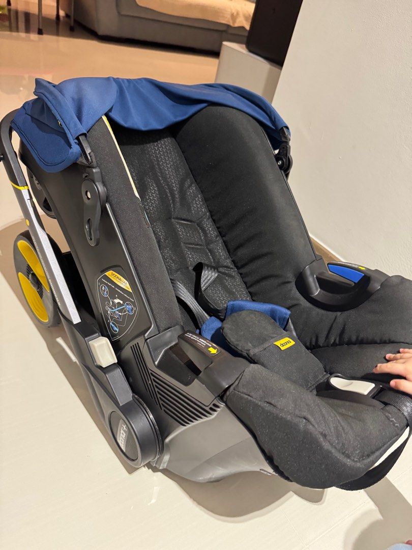 Doona+ Infant Car Seat & Stroller - Navy (Category: Strollers) located in Singapore. Submitted by lynang333 (Listing ID 1379567454, Image 2). Description: This Doona+ infant car seat and stroller is a convenient and safe travel solution. It features a navy blue canopy and a sleek black frame with yellow accents. The integrated wheels make it easy to transition from car seat to stroller. Perfect for parents on the go! Item bought brand new for les