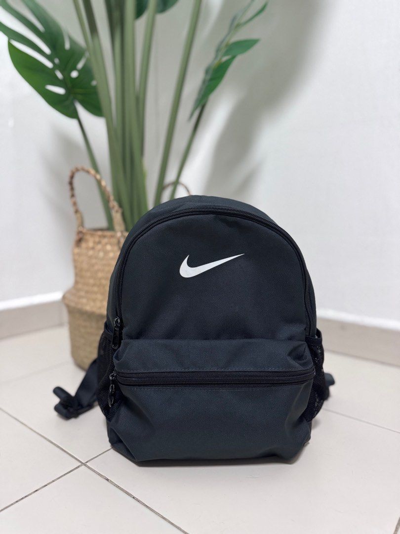 Nike Kids Black Backpack (11L) (Category: Babies & Kids Fashion) located in Singapore. Submitted by ndysff (Listing ID 1378283416, Image 1). Description: Stylish black Nike backpack. Features a front zippered pocket and side mesh pockets. Perfect for everyday use or light travel. The Nike logo is prominently displayed on the front. In excellent condition..