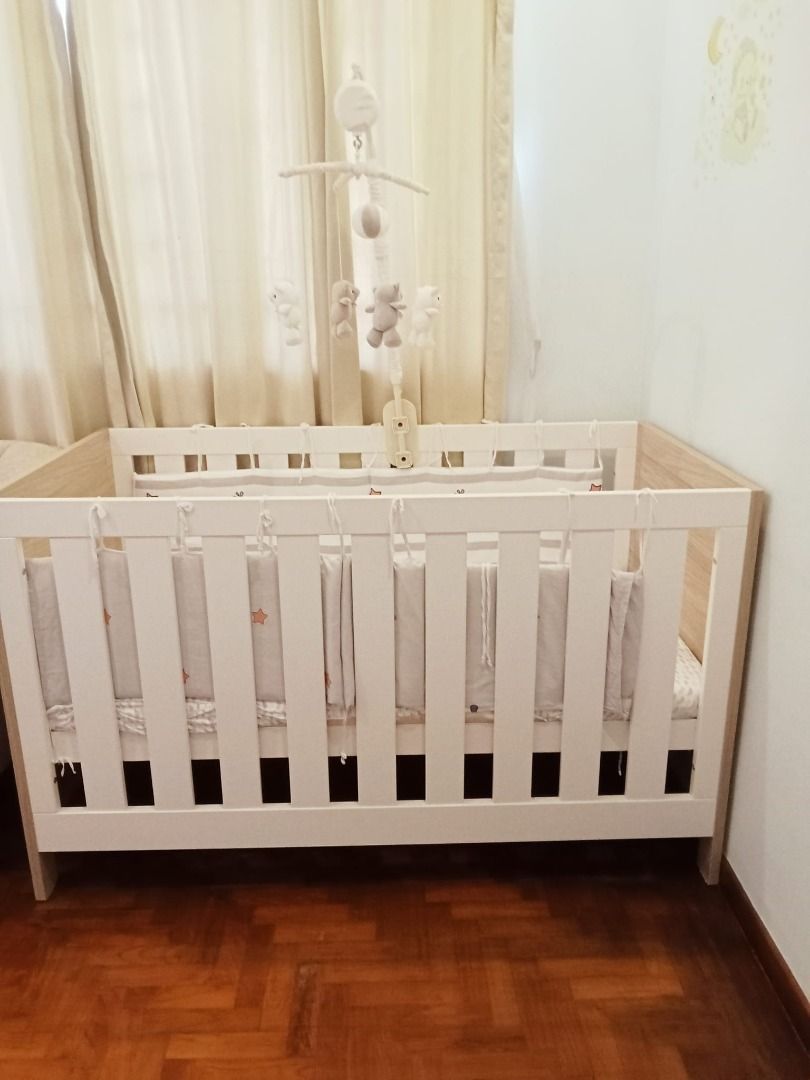 Baby Cot with Mobile (Tutti) (Category: Cots & Cribs) located in Singapore. Submitted by meepokman123 (Listing ID 1378884390, Image 3). Description: Baby cot in good condition, with a built-in mobile. The cot has a white frame with wooden accents. Includes a mattress and bumper pads. Perfect for newborns and young babies. Easy to assemble and disassemble..