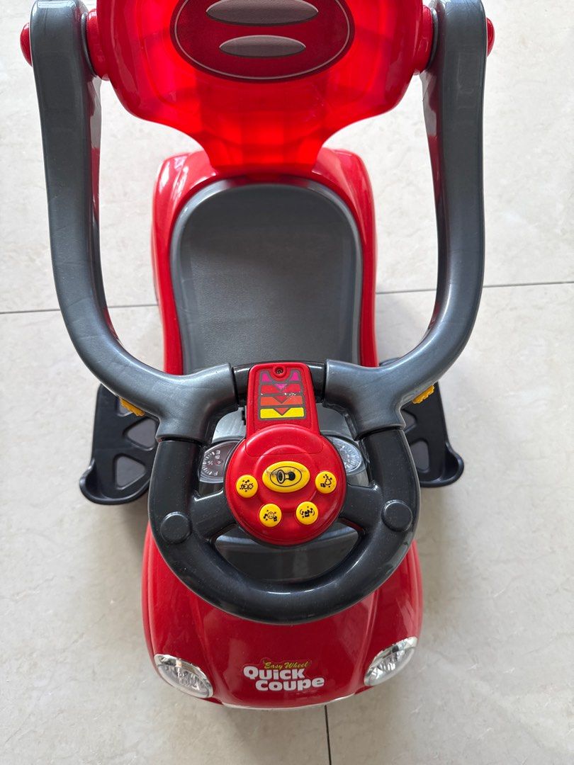 Easy Wheel Quick Coupe Ride-on Car (Category: Infant Playtime) located in Singapore. Submitted by llvelifetothefullest (Listing ID 1378823834, Image 1). Description: This Easy Wheel Quick Coupe ride-on car is in great condition. It features a steering wheel with buttons and a comfortable seat. Perfect for toddlers to enjoy some fun indoors or outdoors. The car is red and has a sleek design..