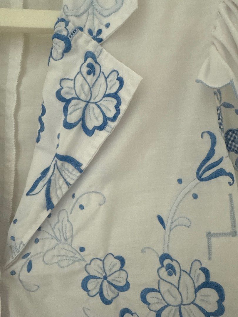 Vintage remake Embroidered White Blouse with Blue Floral Detail (Category: Blouses) located in Singapore. Submitted by jjh2019 (Listing ID 1378967326, Image 2). Description: Beautiful vintage remake white blouse with intricate blue floral embroidery. Features a unique design with ruffled sleeves and a scalloped hem. Includes a single button closure. Perfect for adding a touch of vintage charm to any outfit..