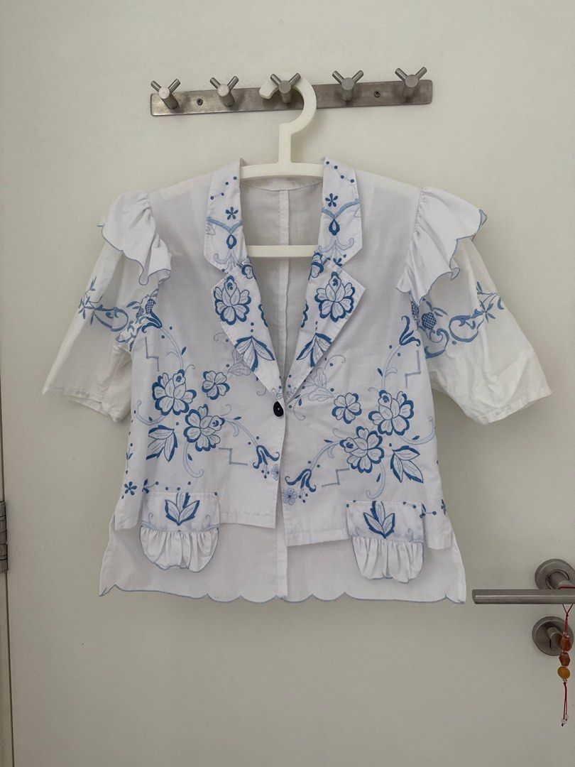 Vintage remake Embroidered White Blouse with Blue Floral Detail (Category: Blouses) located in Singapore. Submitted by jjh2019 (Listing ID 1378967326, Image 1). Description: Beautiful vintage remake white blouse with intricate blue floral embroidery. Features a unique design with ruffled sleeves and a scalloped hem. Includes a single button closure. Perfect for adding a touch of vintage charm to any outfit..