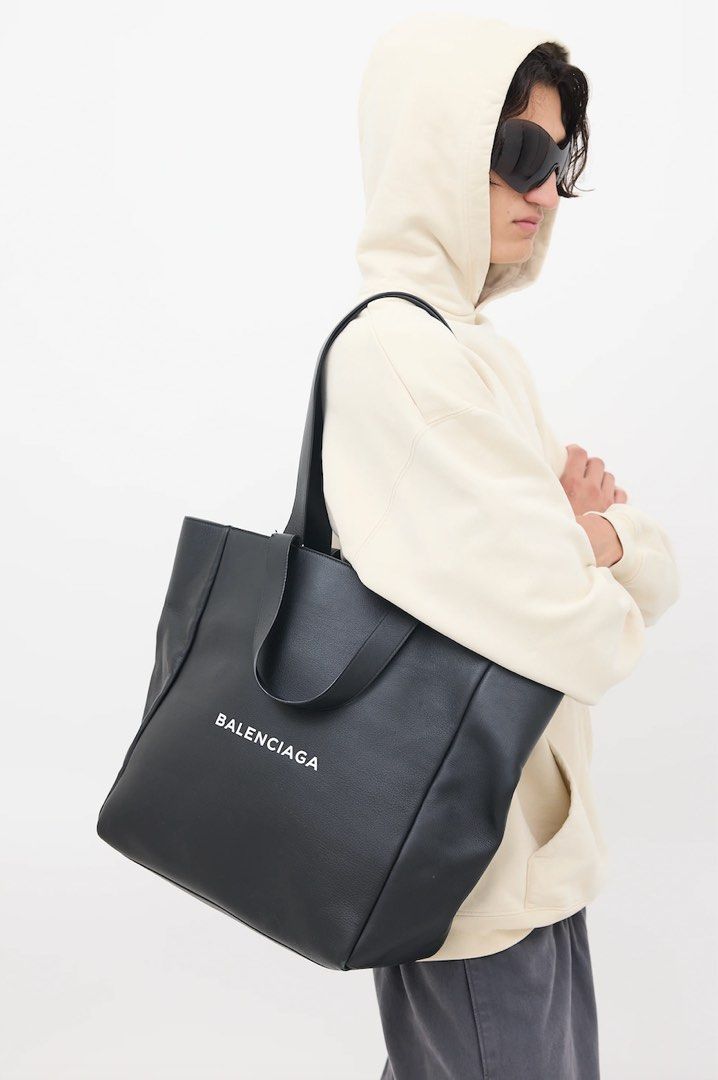 Balenciaga Leather Logo Tote Bag (Category: Luxury Bags & Wallets) located in Pasig City. Submitted by capsulecollection (Listing ID 1379483064, Image 1). Description: Balenciaga Leather Logo Tote Bag Color: Black Tonal stitching White printed embossed logo at front face Four flap top handles to serve as shoulder bag or hand bag Open top One main compartment with two slip zippered pockets Size: 13.5” length x 5” depth x 14” height 7” and 12” top 