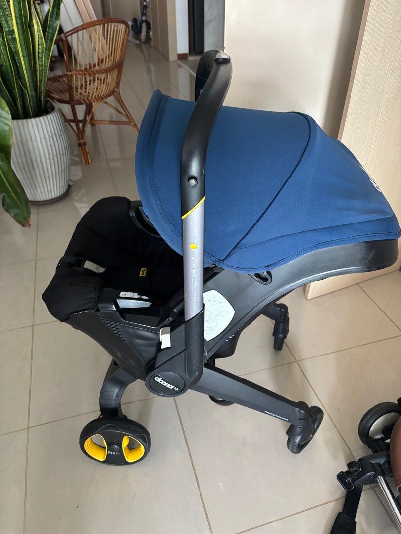 Doona+ Infant Car Seat & Stroller - Black (Category: Strollers) located in Singapore. Submitted by e.vieyen (Listing ID 1379433631, Image 1). Description: This Doona+ car seat and stroller is in great condition. It features a sleek black design with a blue canopy and seat padding. The wheels show some signs of use, but the stroller is fully functional. Includes all safety features and is easy to use. Includes pouch! This car seat expired this yea