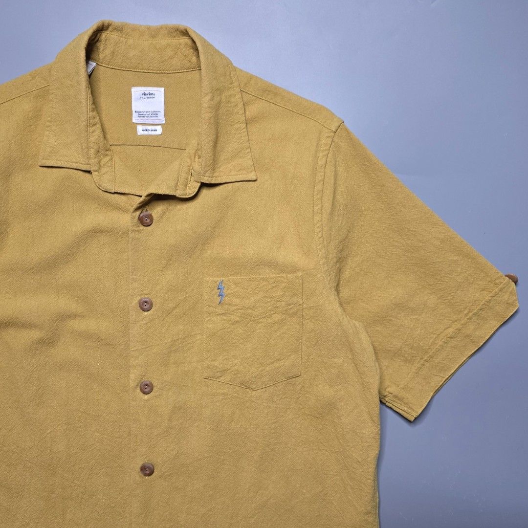 Visvim - SS18 Ellas Shirt - Mustard (Category: Formal Shirts) located in Malabon City. Submitted by buynflex (Listing ID 1379441729, Image 3). Description: Visvim - SS18 Ellas Shirt S/S E. W. - Mustard Size 2 (W 22 X L 28.5 Inches) Gently Used Very Good Condition Product Information Short-sleeved shirt made from linen-silk-cotton blend fabric. One wash Hand stitched detail Original patch detail Original bamboo buttons.