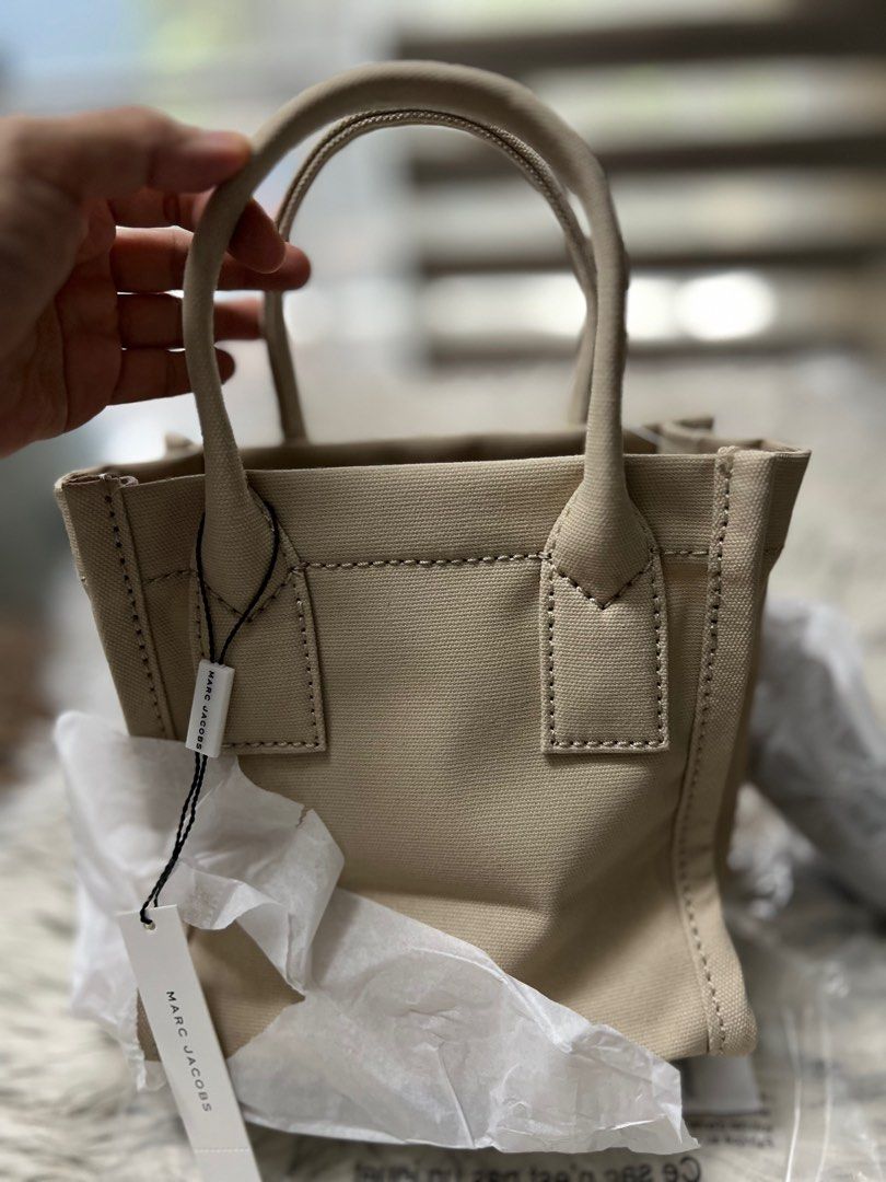 MARC JACOBs Canvas tote (small) (Category: Cross-body Bags) located in Cavite. Submitted by everythingnicehere (Listing ID 1389737758, Image 2). Description: ✨ Condition: 100% Brand New, Never Used ✨ Authenticity: Imported from the US (Original Marc Jacobs) 💯 ✨ Color: Beige ✨ Size: Small Tote ✨ Material: Canvas SIZE & FIT L:20.5cm W:12cm H:22.5cm Handle Drop: 10.5cm Crossbody/ Top Handle Bag Printed Logo on Front Top Zip Closure Removable & Adju