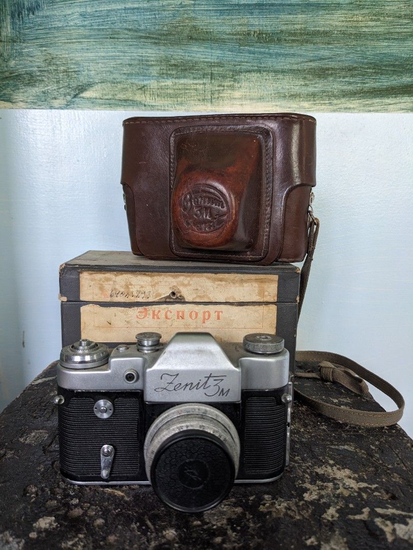 Zenit 3m with box and leather bag (Category: Cameras) located in Goa. Submitted by sofiavill333 (Listing ID 1392705854, Image 1). Description: The Zenit 3M was manufactured in the USSR by KMZ between 1962 and 1970. It uses a 39mm screw-thread mount for interchangeable lenses, but only M39 SLR lenses can be used due to flange distance differences. The camera features a mechanical shutter, a self-timer, and a hinged back cover for easier film loadi