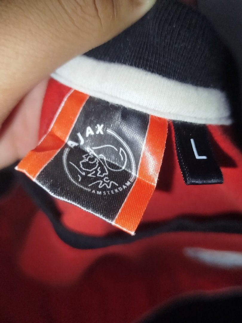 Ajax Amsterdam T-shirt - Size L (Category: Tshirts & Polo Shirts ) located in Manila. Submitted by yanskiezco (Listing ID 1393279632, Image 3). Description: - Ajax Amsterdam T-shirt - Size: L - Color scheme: Red and black - Features the Ajax logo on the front - Back design: "Amsterdam" and "Ajax" - Design: Round neck, short sleeves - Details: White trim around the neck and sides.