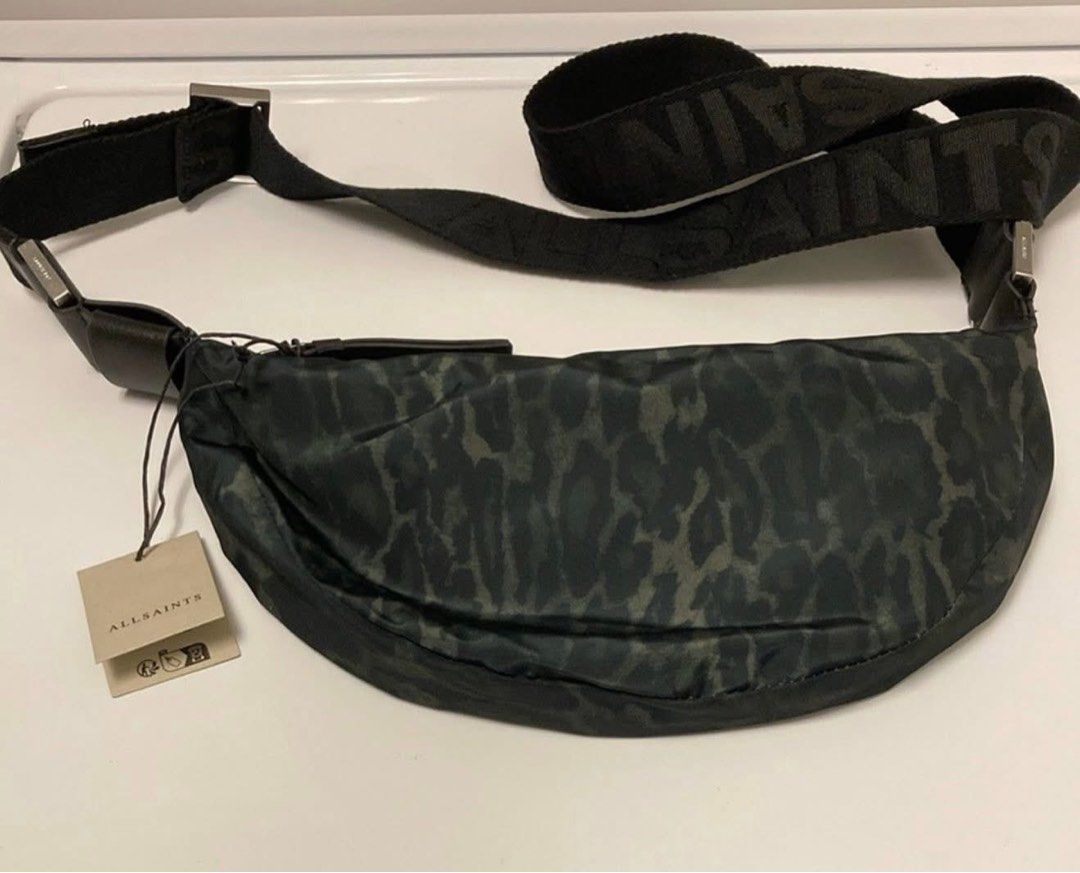 ALL SAINTS Half Moon Crossbody Bag (Category: Cross-body Bags) located in Makati City. Submitted by pick_en_click (Listing ID 1390408440, Image 3). Description: ALL SAINTS Half Moon Crossbody Bag A logo-patterned strap adds a signature flourish to a crescent-shaped crossbody bag patterned in a bold leopard print. • Cotton lining • Textile with leather trim • Leopard Green in color • 4”W x 5 1/2”H x 1 1/2”D (Interior capacity: extra-small.) • 4” -
