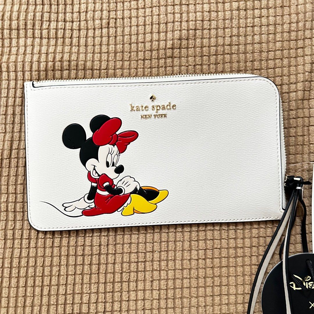 Kate Spade Wristlet (Category: Wallets & Card holders) located in Las Pinas. Submitted by apdeclutter (Listing ID 1393829253, Image 1). Description: The Kate Spade Medium L-Zip Wristlet Disney X Kate Spade New York Minnie is a stylish clutch designed in collaboration with Disney. Made of PVC material with an exterior color of Parchment Multi, this medium-sized wristlet features a zip closure and is adorned with a cute Minnie Mouse design. Perfect