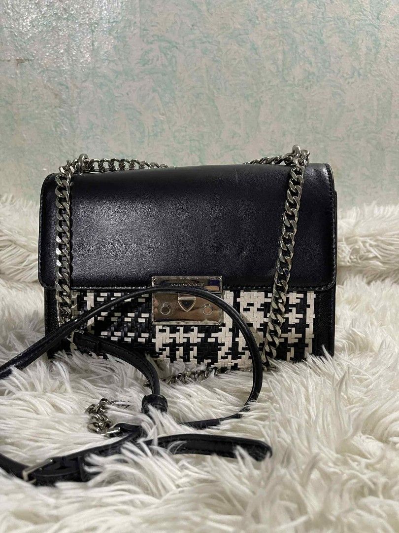 Charles & Keith Black and White Handbag (Category: Luxury Bags & Wallets) located in Santa Rosa. Submitted by zeanncloset (Listing ID 1394212882, Image 1). Description: - Charles & Keith Sling Chained Sling bag - Black and white design - Woven front panel - Black leather top - Silver chain strap - Silver clasp closure - Pink interior - Small back pocket - Approximately 7 inches wide.