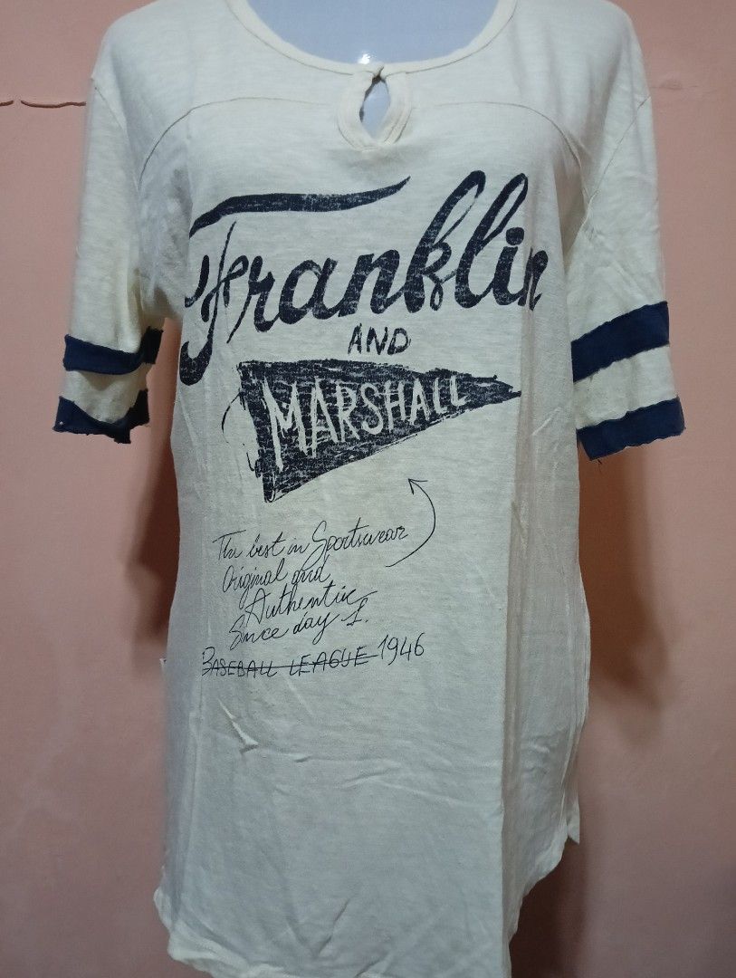 Franklin & Marshall Baseball League T-shirt (Category: Tshirts & Polo Shirts ) located in Manila. Submitted by queenv_22 (Listing ID 1394299522, Image 1). Description: Cream-colored Franklin & Marshall T-shirt with navy blue stripes on the sleeves. Features a keyhole neckline and a large "Franklin and Marshall" graphic on the front. The shirt also has text that reads "The best in Sportswear, Original, Genuine, Authentic, Since day's, BASEBALL LEA