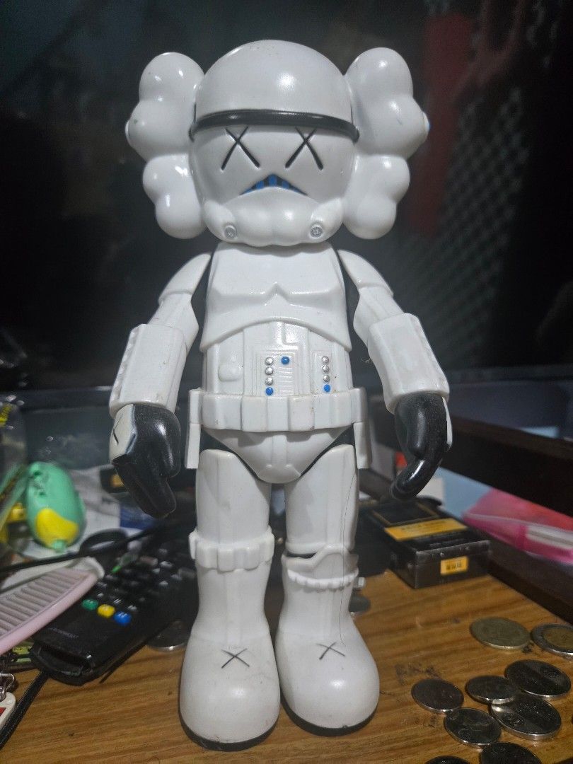 KAWS Stormtrooper Figure (Category: Figurines & Statues) located in Manila. Submitted by ritzselect26 (Listing ID 1394432073, Image 1). Description: - KAWS Stormtrooper figure - Features KAWS signature design - Iconic X eyes and hands - Color: White with black accents and blue eyes - Marked with "Designed by KAWS" - Marked with "MEDICOMTOY 2006 CHINA".