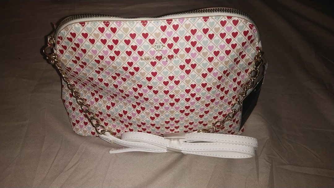 Nanette Lepore Heart Print Bag (Category: Cross-body Bags) located in Las Pinas. Submitted by younggem.d97325 (Listing ID 1394426691, Image 2). Description: Nanette Lepore bag features a heart print design. It has a gold chain strap and a white strap. The bag has a zipper closure and an interior pocket. The tag indicates the style name is "Marble Solid Bag in a Bag" and the color is "Tan Sunny Stripes". Price: ₱750 fixed Issue: Has a stain but is