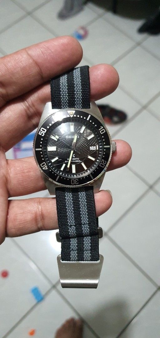 Seiko Mod 62mas Watch with Black Dial (Category: Luxury Watches) located in Lapu Lapu. Submitted by watchenthusiast4444 (Listing ID 1394430704, Image 2). Description: - Seiko watch with a black dial Seiko nh35 Automatic movement - Luminous hands and markers - Rotating bezel - Black and gray striped NATO strap - Stainless steel case - Date display at 3 o'clock.