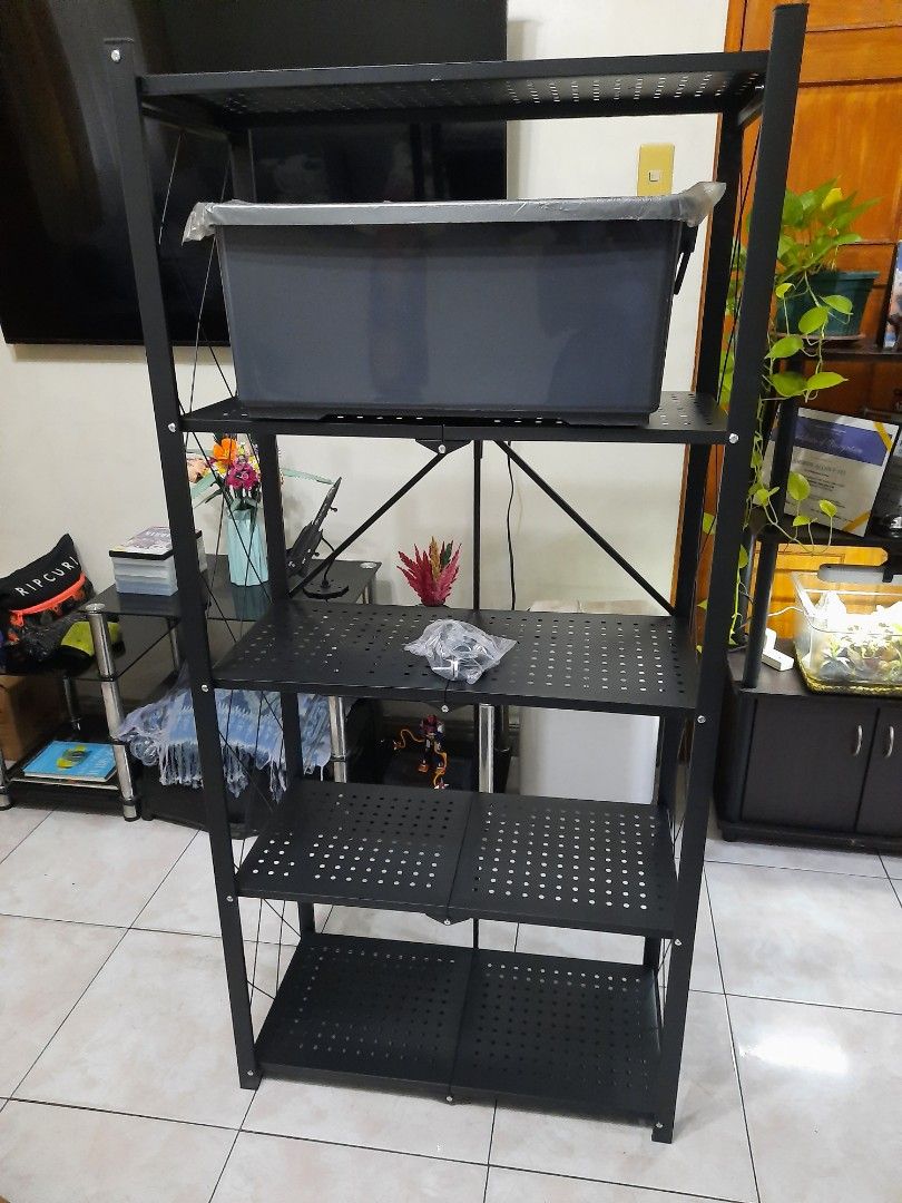 Foldable 5-Tier Bookshelf (Category: Shelves, Cabinets & Racks) located in Quezon City. Submitted by henco (Listing ID 1394605687, Image 3). Description: - 5-tier foldable bookshelf - Black metal frame with diamond design - Dark-colored shelves - Equipped with wheels for easy movement - Ideal for books, plants, and various items - pls call for fast transaction 09279957180.