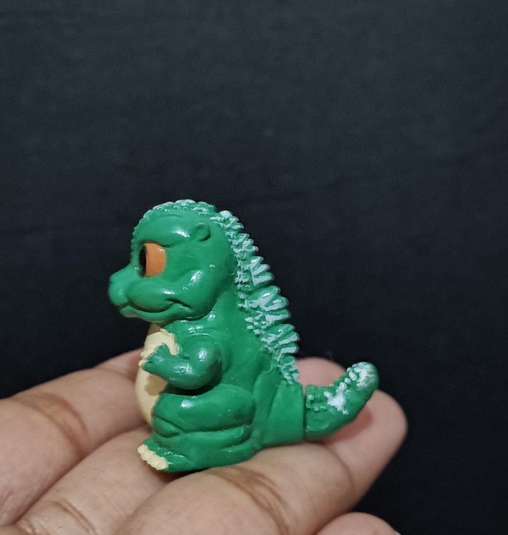 Godzilla Toy Figure (Category: Figurines & Statues) located in Compostela. Submitted by buenaflora04681 (Listing ID 1394682364, Image 2). Description: - Godzilla figure - Green body with cream belly - Orange eyes - Detailed dorsal fin - Small size - Made of plastic - Collectible item - Perfect for Godzilla fans.
