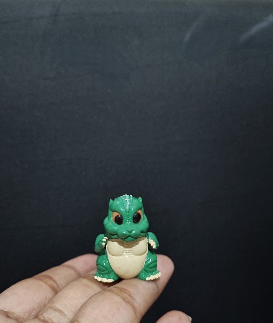 Godzilla Toy Figure (Category: Figurines & Statues) located in Compostela. Submitted by buenaflora04681 (Listing ID 1394682364, Image 1). Description: - Godzilla figure - Green body with cream belly - Orange eyes - Detailed dorsal fin - Small size - Made of plastic - Collectible item - Perfect for Godzilla fans.