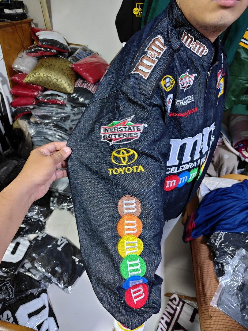 M&M's Racing Jacket (Category: Coats, Jackets and Outerwear) located in Pandi. Submitted by yanyan_apparel.store08 (Listing ID 1394647445, Image 3). Description: Remake Remake - Dark denim jacket - Features patches: M&M's, Toyota, Interstate Batteries - Celebrates M&M's 75th anniversary - Front zipper closure - Ribbed cuffs with M&M's branding - Large M&M's and Toyota logos on back - Number 18 on sleeves.