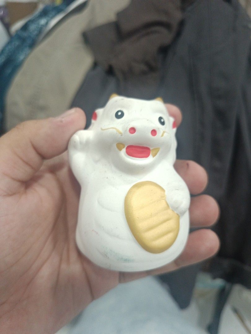 White Ceramic Lucky Dragon Figurine (Category: Other Home Decor) located in Quezon City. Submitted by bjetp (Listing ID 1394763409, Image 1). Description: - Adorable ceramic figurine - White body with gold coin and red accents - Smiling face with black eyes - Features yellow horns - Waving hand gesture - Unique and charming decorative item.