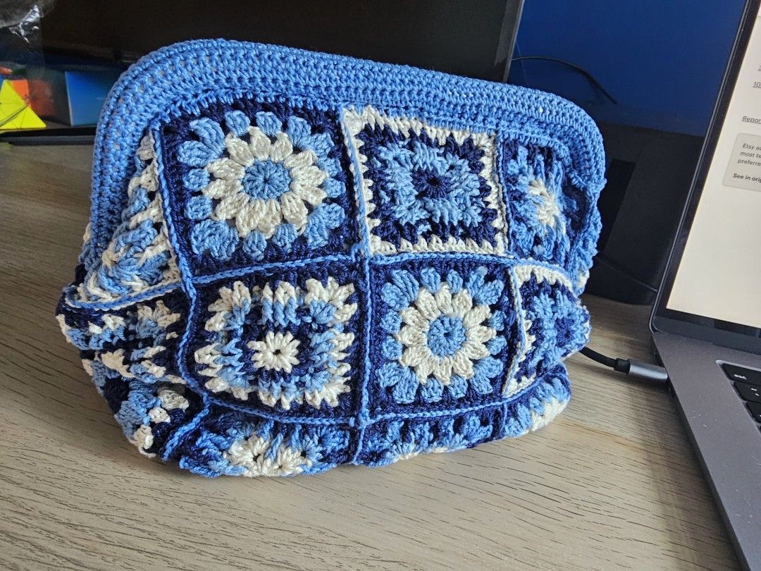 Handmade Crochet Clutch Bag - Blue (Category: Clutches) located in Makati City. Submitted by styledge.ph (Listing ID 1394874389, Image 2). Description: Handmade clutch bag features a beautiful crochet design in shades of blue and white. It has a rectangular shape with a frame closure. The bag is made of multiple crochet squares, creating a unique and stylish look. Perfect for carrying essentials, this clutch is a fashionable accessory for any occ