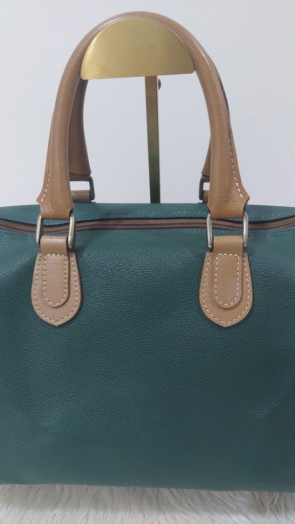 Lancel Paris Green Handbag (Category: Luxury Bags & Wallets) located in Cainta. Submitted by pouchbucketbags (Listing ID 1394903477, Image 2). Description: - Lancel Paris handbag - Striking green color with tan accents - Dual top handles - Structured design - Matching tan fabric interior - Rectangular shape - Zipper closure - Brand label visible inside - Made in France - 9"H × 7"W × 14"L .
