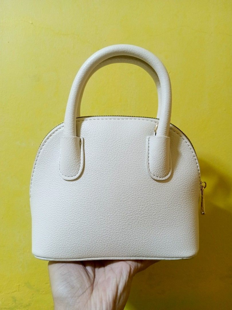 Mumu Select Dome Handbag - Beige White (Category: Luxury Bags & Wallets) located in Quezon City. Submitted by alibalza (Listing ID 1394951212, Image 2). Description: - Beige White-colored Mumu Select dome handbag - Top handle and detachable shoulder strap - Textured exterior - Gold-colored zipper and hardware - Brown interior lining - Includes dust bag RFS: not my style, used only once. MOP: Gcash, Maya, Maribank/Seabank 📍North Caloocan/Nova QC.