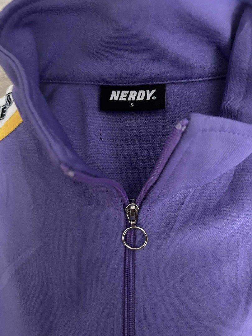 Nerdy Tracksuit Set - Purple (Category: Sets & Coordinates) located in Calamba. Submitted by merrymerida (Listing ID 1394789434, Image 3). Description: - Nerdy tracksuit set - Color: Purple - Includes: Zip-up jacket and matching pants - Jacket features: Nerdy logo, stripe detailing, high collar, front pockets, size S - Pants features: Nerdy logo, stripe detailing, elastic waistband, drawstring, size M - Made in Vietnam.