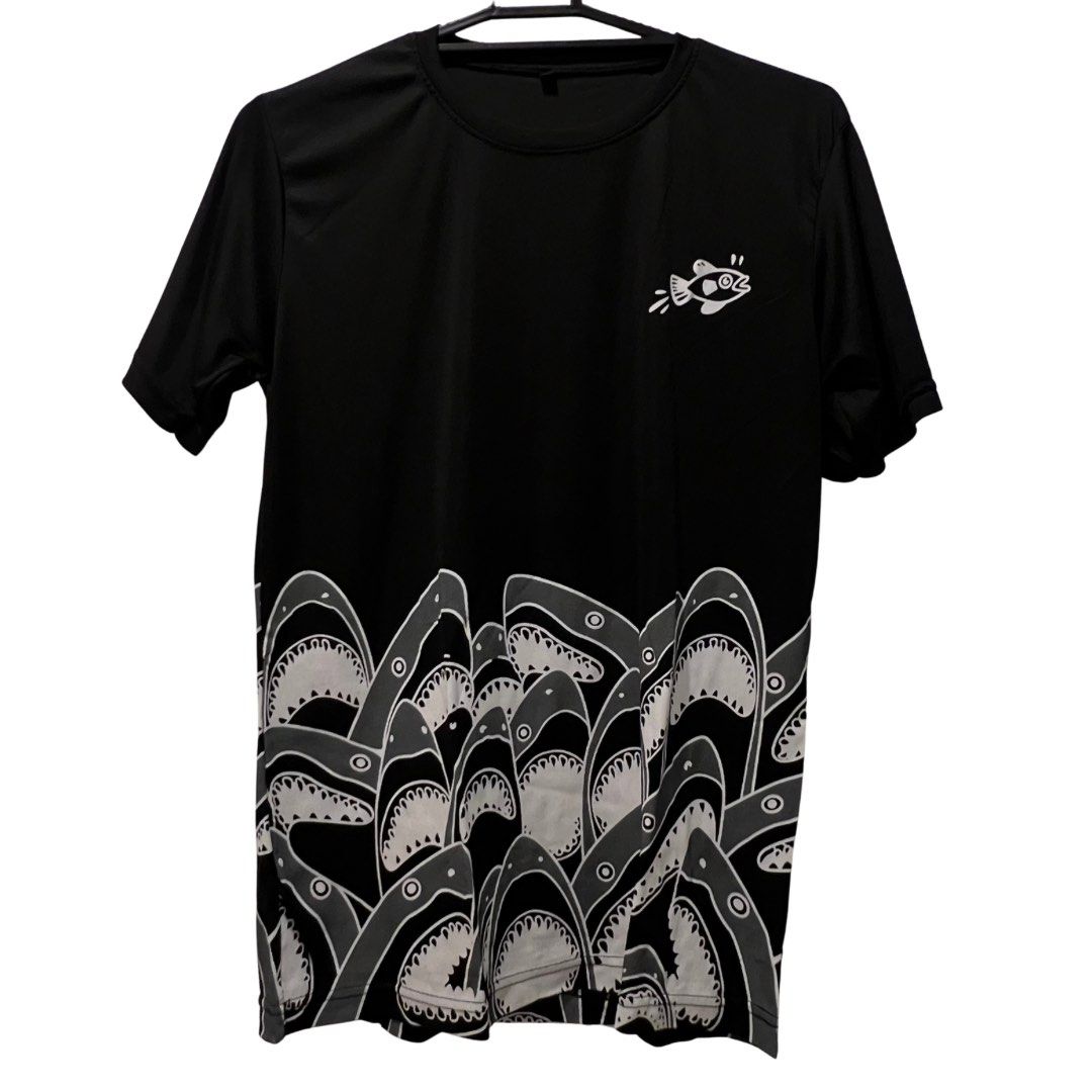 Black Shark Graphic T-Shirt (Category: Tshirts & Polo Shirts ) located in Quezon City. Submitted by zhobby (Listing ID 1395064975, Image 1). Description: - Black short-sleeved t-shirt - Features a shark graphic - Small fish graphic on the upper chest - Repeating shark mouth design at the bottom.