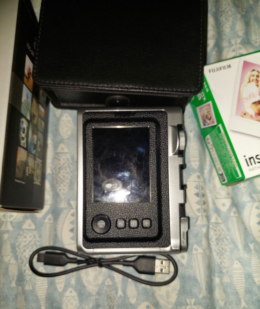 Fujifilm Instax Mini Evo Instant Camera (Category: Cameras) located in Manila. Submitted by mpxlive (Listing ID 1395021409, Image 3). Description: - Fujifilm Instax Mini Evo instant camera - Stylish silver and black design - Includes a black leather case - Comes with a charging cable - Original box included - Bought last June 6, 2025 - Used outside twice (company event and SHS Graduation); used a few times to print at home. Freebies: Free 20 Shee