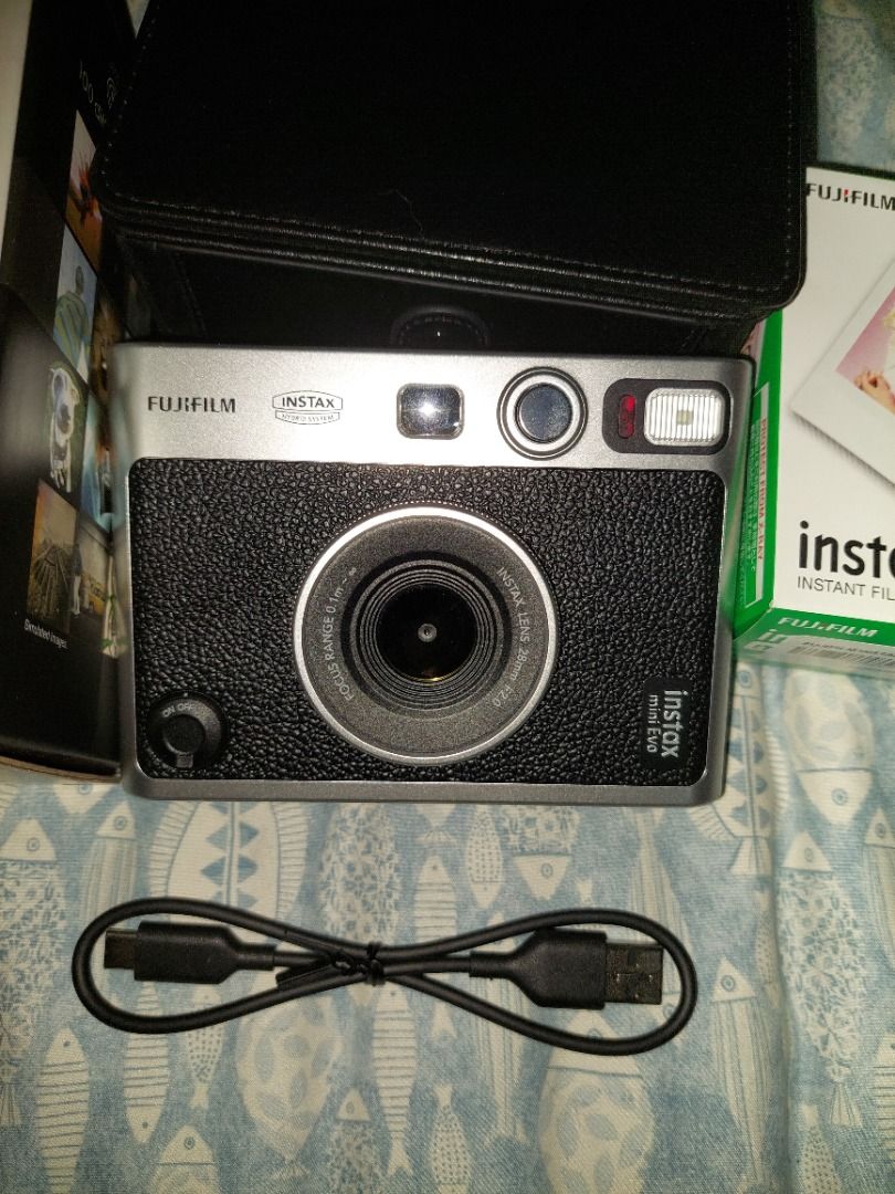 Fujifilm Instax Mini Evo Instant Camera (Category: Cameras) located in Manila. Submitted by mpxlive (Listing ID 1395021409, Image 2). Description: - Fujifilm Instax Mini Evo instant camera - Stylish silver and black design - Includes a black leather case - Comes with a charging cable - Original box included - Bought last June 6, 2025 - Used outside twice (company event and SHS Graduation); used a few times to print at home. Freebies: Free 20 Shee