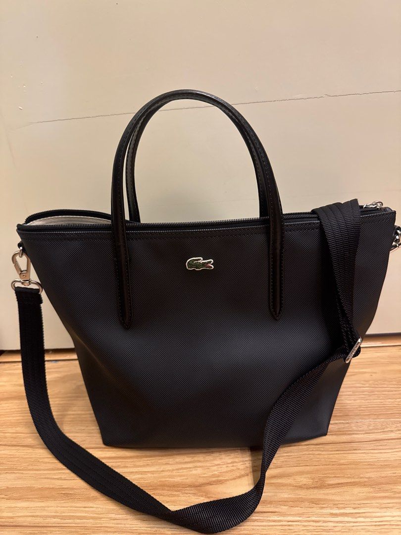 Lacoste Black Tote Bag with Shoulder Strap (Category: Tote Bags) located in Consolacion. Submitted by jesfats (Listing ID 1394975043, Image 1). Description: - Black Lacoste tote bag - Detachable and adjustable shoulder strap - Top zipper closure - Two handles - Small silver Lacoste logo - Textured material.
