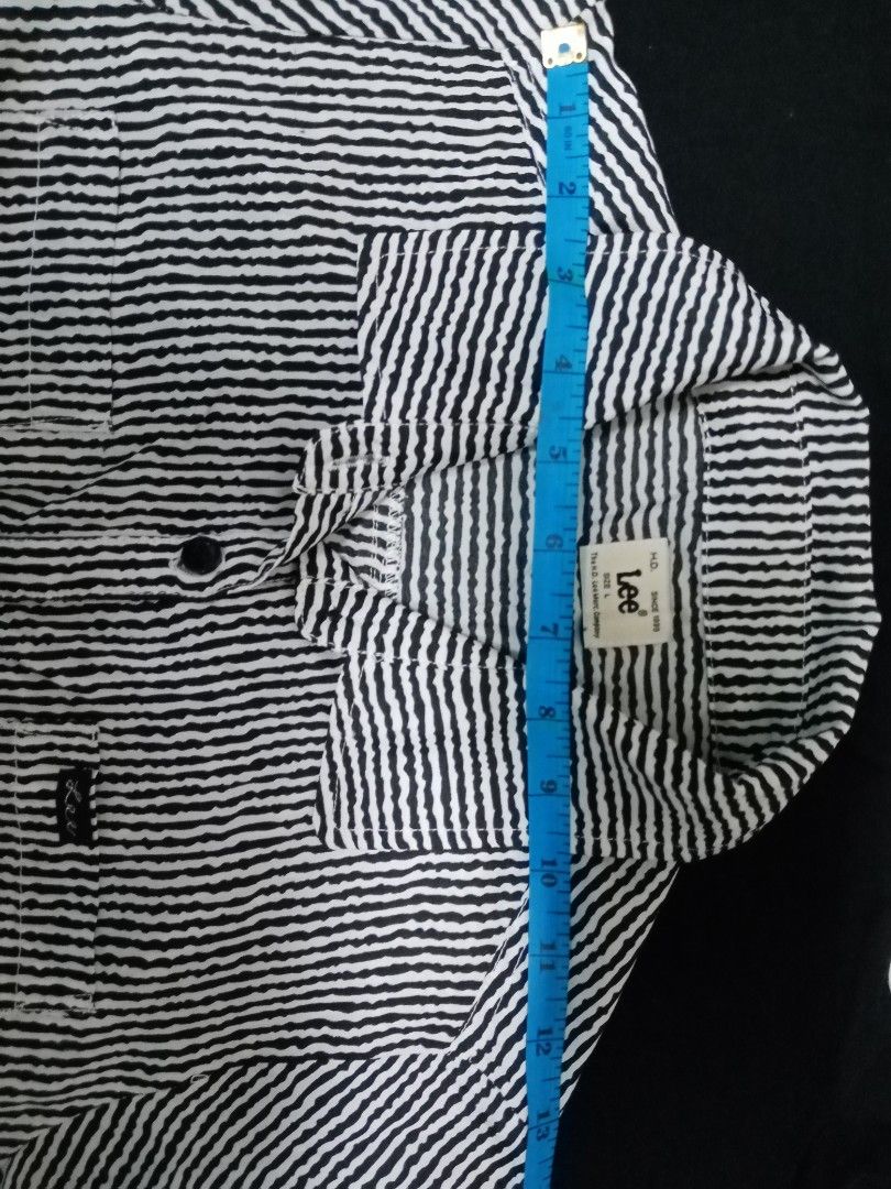 Lee Striped Button-Up Shirt (Category: Blouses) located in Makati City. Submitted by comoro (Listing ID 1394982536, Image 2). Description: Lee button-up shirt features a black and white striped pattern. It has two chest pockets and a collar. The shirt has a button closure and short sleeves. The measurements are approximately 13 inches across the chest and 28 inches in length. The Lee logo is visible on the pocket..