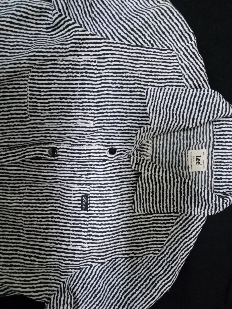 Lee Striped Button-Up Shirt (Category: Blouses) located in Makati City. Submitted by comoro (Listing ID 1394982536, Image 1). Description: Lee button-up shirt features a black and white striped pattern. It has two chest pockets and a collar. The shirt has a button closure and short sleeves. The measurements are approximately 13 inches across the chest and 28 inches in length. The Lee logo is visible on the pocket..