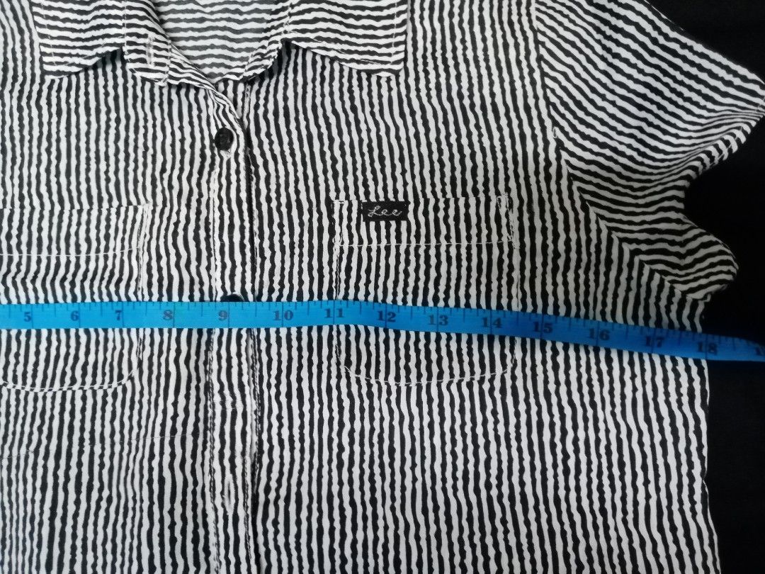 Lee Striped Button-Up Shirt (Category: Blouses) located in Makati City. Submitted by comoro (Listing ID 1394982536, Image 3). Description: Lee button-up shirt features a black and white striped pattern. It has two chest pockets and a collar. The shirt has a button closure and short sleeves. The measurements are approximately 13 inches across the chest and 28 inches in length. The Lee logo is visible on the pocket..