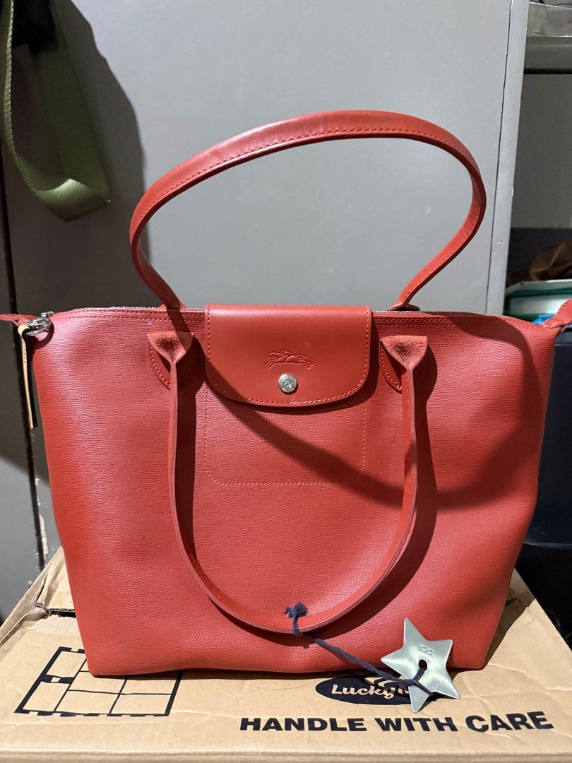 Longchamp Le Pliage Tote Bag From HKIA (Category: Luxury Bags & Wallets) located in Paranaque City. Submitted by jb38388 (Listing ID 1394986421, Image 1). Description: Longchamp “Le Pliage City” tote bag in PVC and leather Flat shoulder straps Center flap with snap/zip top closures Lining: polyester Approx. 10.4”H x 11”W x 6.1”D Bought in Hongkong Intl Airport Brand longchamp Color terracotta Highlights cognac brown calf leather smooth grain two 