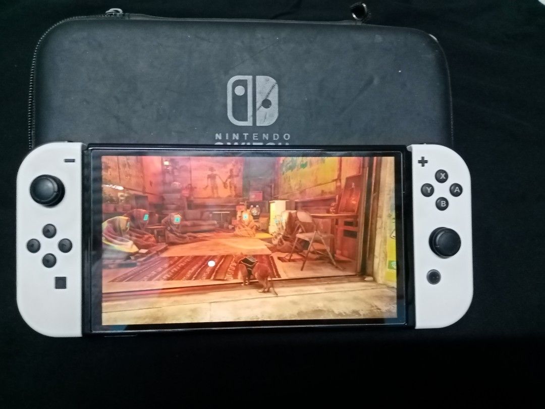 nintendo switch (Category: Controllers) located in Makati City. Submitted by comoro (Listing ID 1394984697, Image 2). Description: - Nintendo Switch OLED Model (White Joy-Cons) - Includes: Console, Joy-Con controllers, Joy-Con grip, charging cable, and box - Screen displays a game.